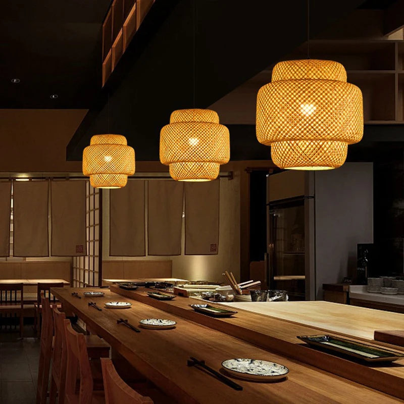Three ZenWeave 'Tiered Serenity' bamboo pendants hanging over a modern sushi bar, casting a warm, inviting light and creating an authentic, serene oriental atmosphere. VelunaLumin.