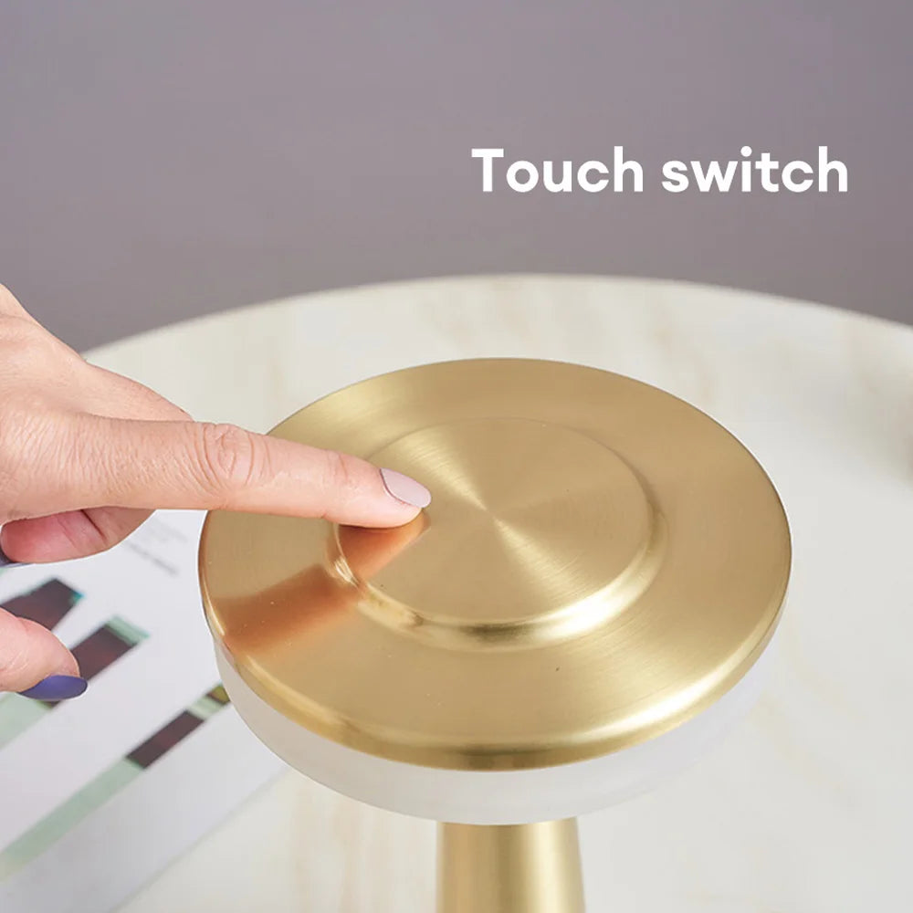 Close-up of a hand touching the top of the AuraGlow Cordless Touch Lamp to adjust brightness and light color. VelunaLumin.