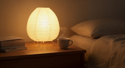 Akari Rice Paper Table Lamp on a minimalist bedside table, providing a serene and cozy ambient light in a modern Japandi-style bedroom. VelunaLumin