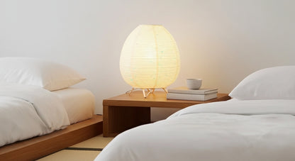 Akari Rice Paper Table Lamp on a minimalist bedside table, providing a serene and cozy ambient light in a modern Japandi-style bedroom. VelunaLumin.