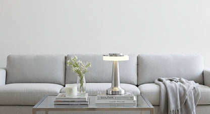 AuraGlow Cordless Touch Lamp in Silver on a modern bedside table, casting a cozy, dimmable warm light in a minimalist bedroom. VelunaLumin.