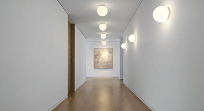 A series of AuraOrb Minimalist Ceiling Lights in Gold and Black illuminating a modern hallway, creating a rhythmic and serene path of light. VelunaLumin.