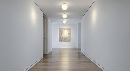 A series of AuraOrb Minimalist Ceiling Lights in Gold and Black illuminating a modern hallway, creating a rhythmic and serene path of light. VelunaLumin.