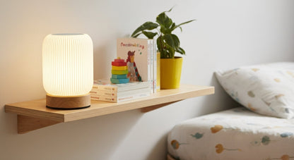 AuraShroom Portable Touch Lamp on a bedside table, casting a soft, warm glow in a cozy modern bedroom, perfect as a night light. VelunaLumin.