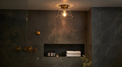 A single AuraSphere Ceiling Light in a Transparent glass finish providing clean, spa-like illumination in a luxurious modern bathroom. VelunaLumin.