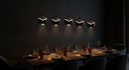 A linear arrangement of five AuraSpire pendants in Matte Black illuminating a long, dark wood dining table for a dramatic effect. VelunaLumin.