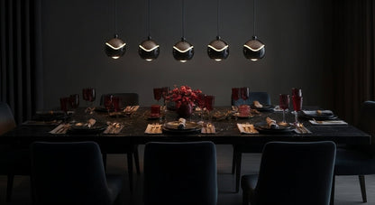 A linear arrangement of five AuraSpire pendants in Matte Black illuminating a long, dark wood dining table for a dramatic effect. VelunaLumin.