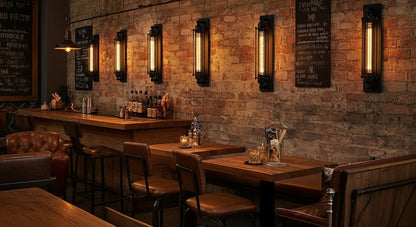 Line of IronGlow Industrial Wall Sconces illuminating a brick wall in a trendy industrial bar, creating an authentic, warm, and inviting ambiance. VelunaLumin.

