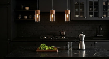 Two LuminaGrace Nordic Wood & Cognac Glass Tall Cylinder Pendant Lights hanging above a modern wooden dining table, casting a warm amber glow, creating an inviting atmosphere, VelunaLumin.