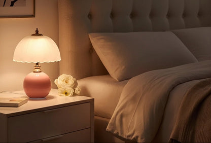 NouveauGlow Murano-Style Mushroom Lamp in Pastel Pink on a bedside table, casting a soft, dimmable warm light in a modern bedroom. VelunaLumin.