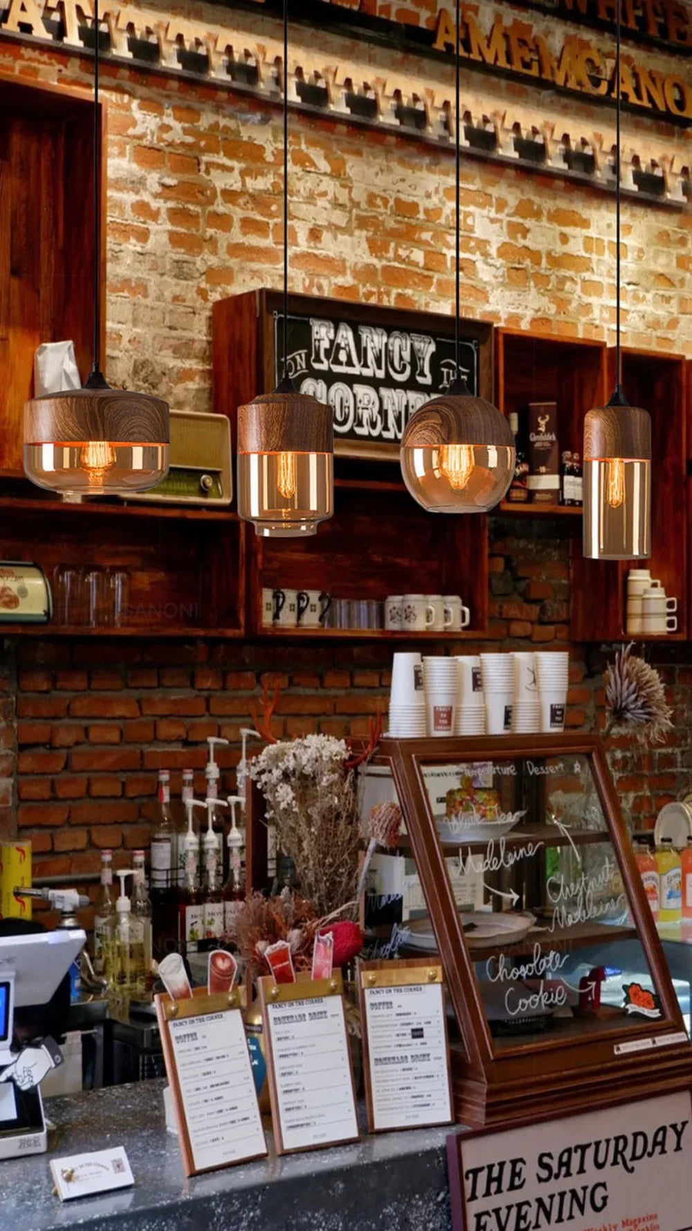 Two LuminaGrace Nordic Wood & Cognac Glass Tall Cylinder Pendant Lights hanging above a modern wooden dining table, casting a warm amber glow, creating an inviting atmosphere, VelunaLumin.