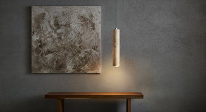 TerraGlow Natural Stone Pendant Light illuminating a textured abstract artwork, highlighting both the lamp's unique stone and the art's details in a minimalist gallery setting. VelunaLumin.